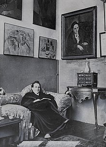 Gertrude Stein sitting on a sofa in her Paris studio